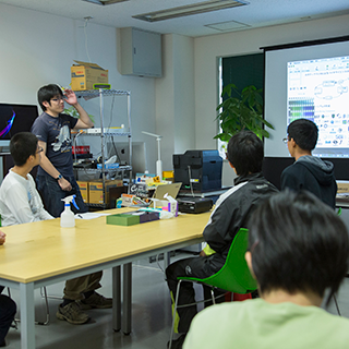 見学の高校生に説明する関特任助教　合成生物学分野　谷内江研究室